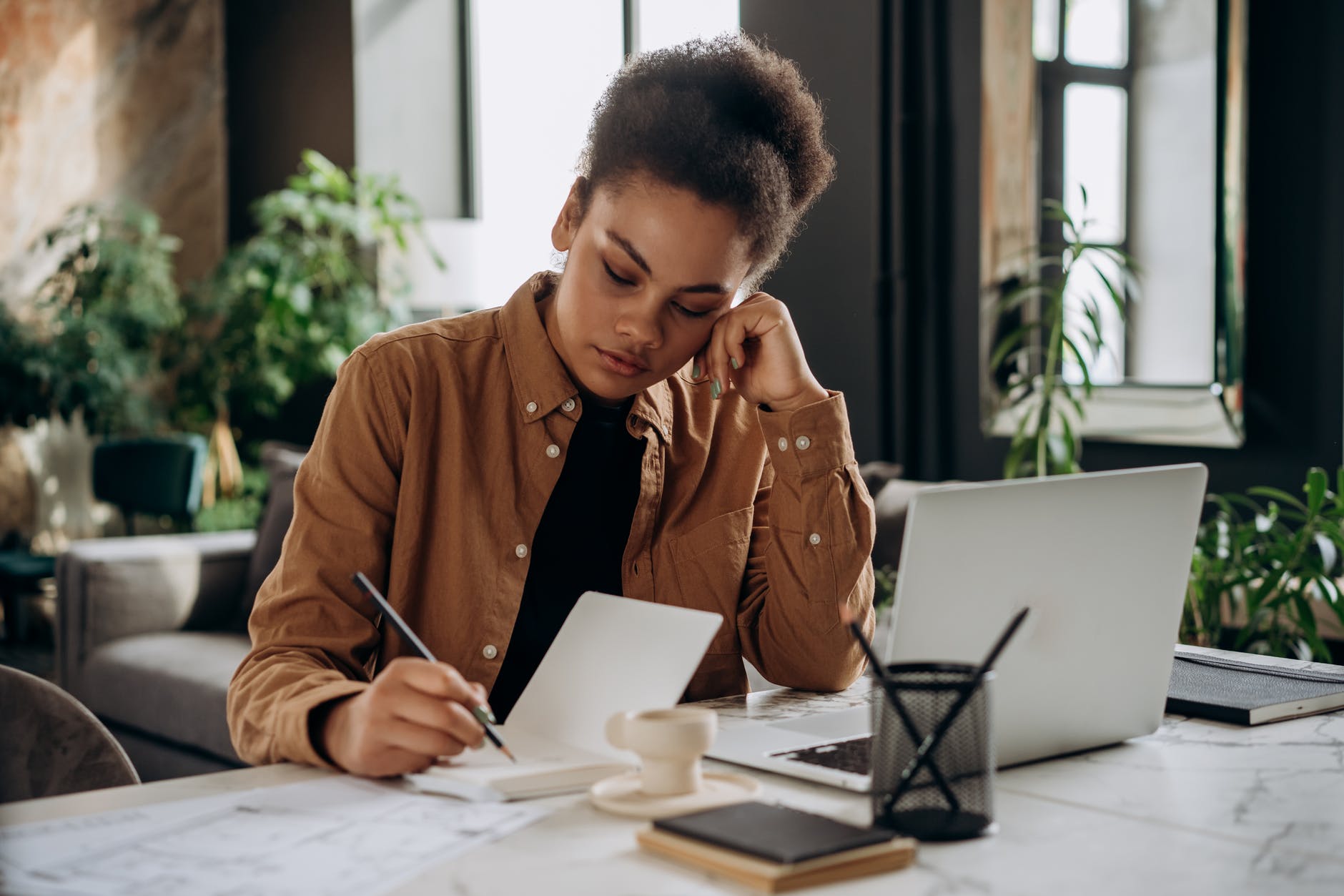 Picture of brown girl looking frustratedly at a notebook.